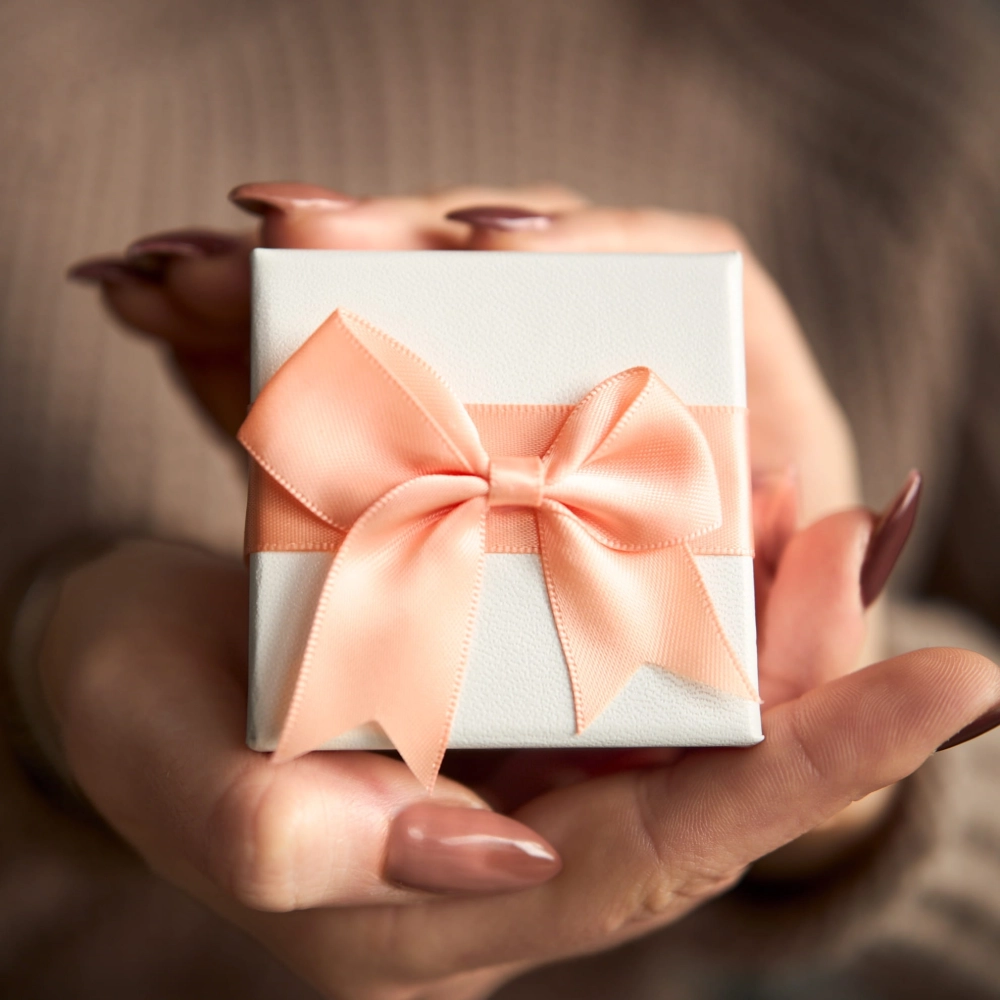 Białe pudełko prezentowe NOVADI z brzoskwiniową kokardą widok pod kątem